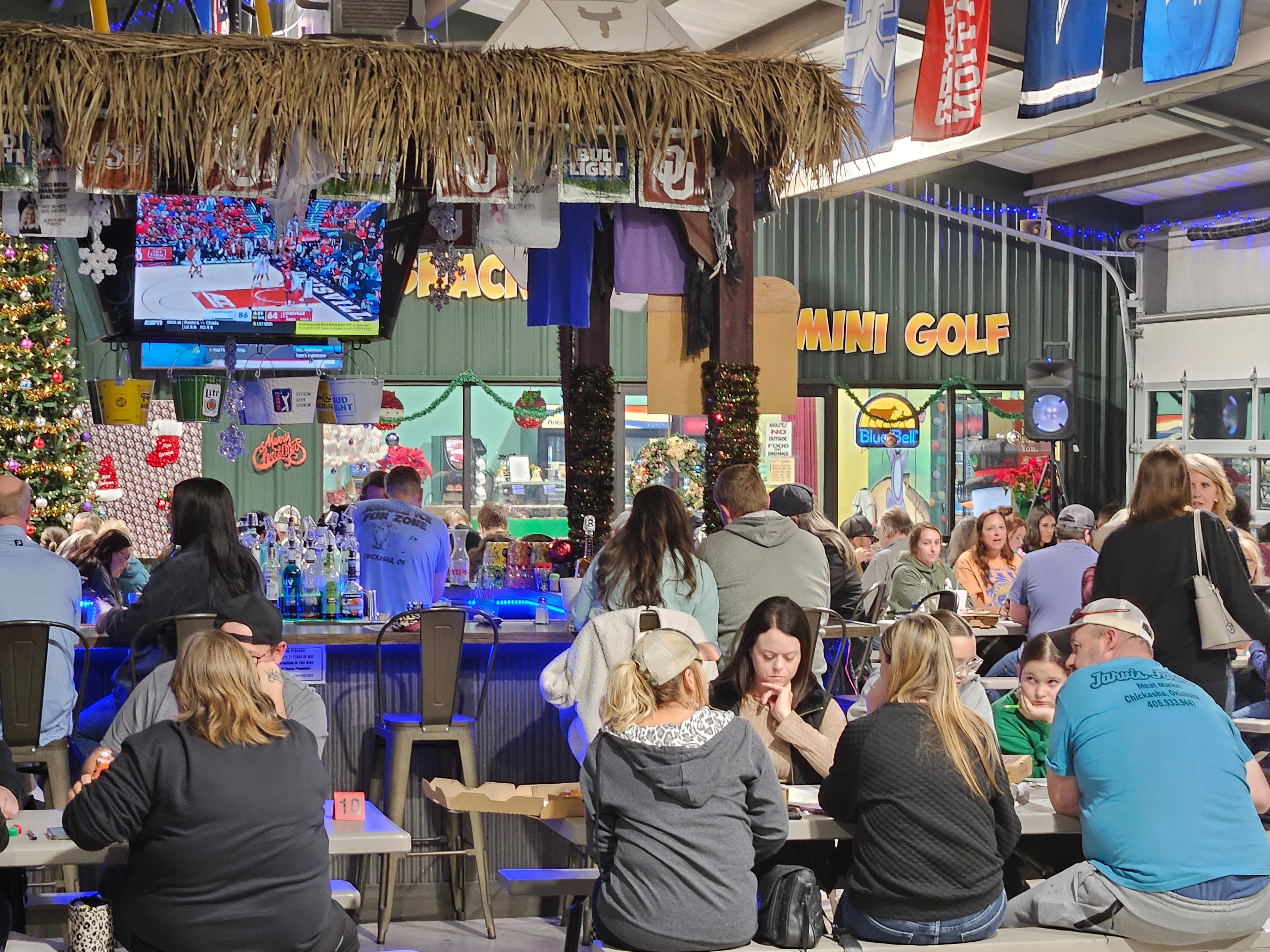 Packed house at Jungle Ice Fun Zone during the Christmas season with the Tiki Bar and Mini Golf sign visible